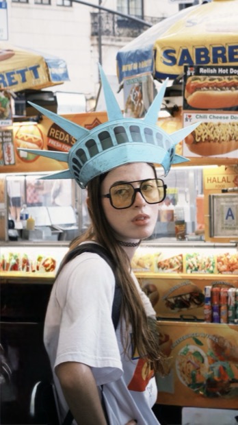 Girl in a Statue of Liberty crown at a hot dog stand